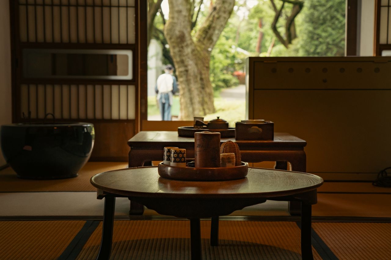 物件管理 Japanese tea room interior with view of garden and person outside.